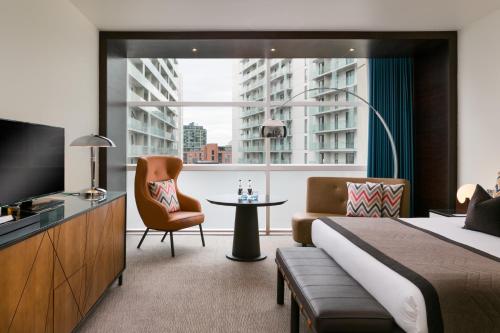 a hotel room with a bed and a tv and a chair at The Lowry Hotel Manchester in Manchester