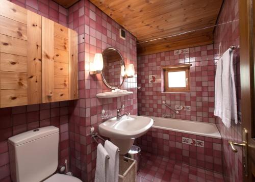a pink tiled bathroom with a sink and a toilet at Arena Lodge in Flims
