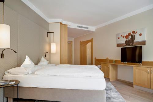 a hotel room with a bed and a television at Hotel Burggräflerhof in Merano