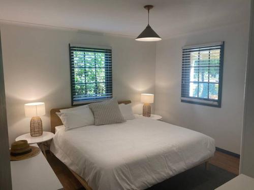 1 dormitorio blanco con 1 cama y 2 ventanas en Cook's Cottage in Balhannah, en Balhannah