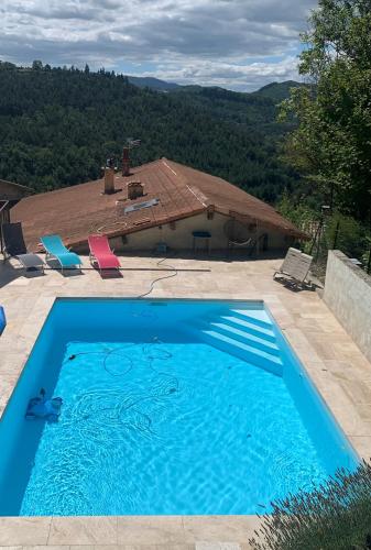 - une piscine bleue avec vue sur une maison dans l'établissement Gîte Le doux Valoan, à Lamastre