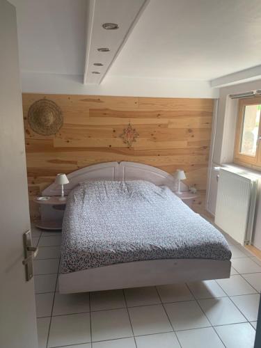 1 dormitorio con 1 cama con pared de madera en Gîte Le doux Valoan, en Lamastre