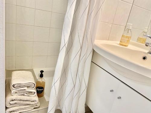 a bathroom with a shower curtain next to a sink at Appartement en face Hopital Nord in Saint-Priest-en-Jarez