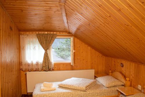 a bedroom with a bed in a wooden house at Pensiunea Casa Ioana in Şugag