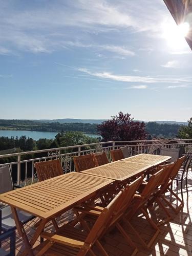 a wooden table sitting on top of a deck with chairs at Vaste villa en position dominante superbe vue lacs in Hautecour