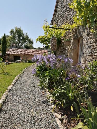 un chemin de jardin en face d'une maison en pierre dans l'établissement Chambre d'hôtes le chat botté, à Espédaillac