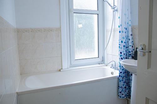 baño con bañera, lavabo y ventana en Central Dover - 1 Bedroom apartment, en Kent