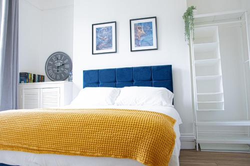 a bedroom with a blue headboard and a clock on the wall at Central Dover - 1 Bedroom apartment in Kent