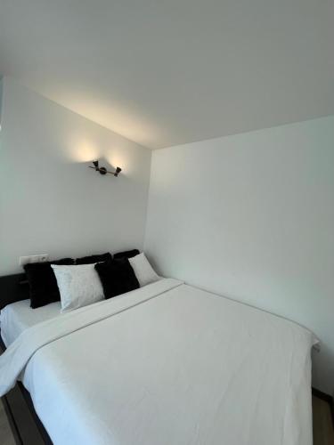 uma cama branca com almofadas pretas num quarto em Studio apartment em Valmiera