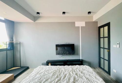 a bedroom with a bed and a tv on the wall at Yi Piao B&B in Zhushan