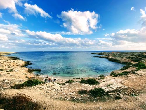 un grupo de personas de pie en las rocas cerca del océano en Appartamento con giardino en Lampedusa