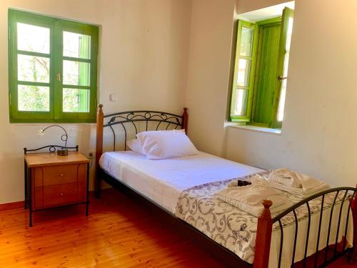 a bedroom with a bed and a table and two windows at Petra Maisonettes in Kariá
