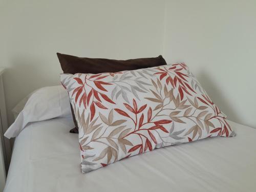 a red and white pillow on a bed at Apartamento a Carballeira in Lugo