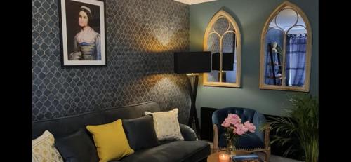 a living room with a black couch and two mirrors at Stylish Scottish House with garden and parking in Perth