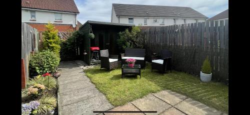 a small backyard with chairs and a table and a fence at Stylish Scottish House with garden and parking in Perth