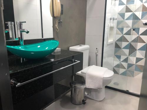 La salle de bains est pourvue d'un lavabo vert et de toilettes. dans l'établissement Flat Vila Olímpia ao lado do Shopping, à São Paulo