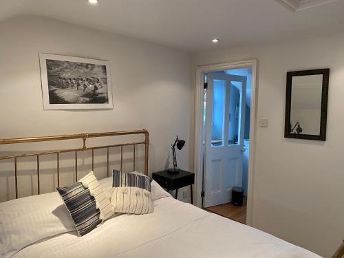 a bedroom with a bed with white sheets and a mirror at Chapel Place in Ermington