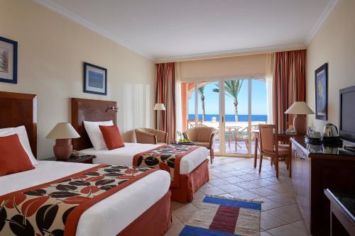a hotel room with two beds and a view of the ocean at Jaz Grand Marsa in Coraya Bay