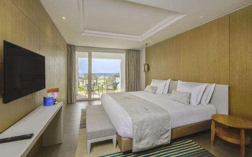 a hotel room with a large bed and a television at Royal Azur Thalassa in Hammamet