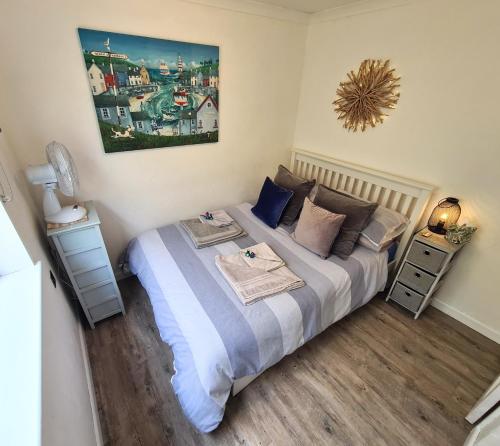 a bedroom with a bed and a painting on the wall at Knobbly Nook, whole property, gardens, parking, wifi, relaxing near Eden Project and coast in Saint Blazey