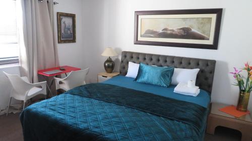 a bedroom with a bed with a blue comforter at Galaxy Sleep And Go Rooms Goodwood in Cape Town