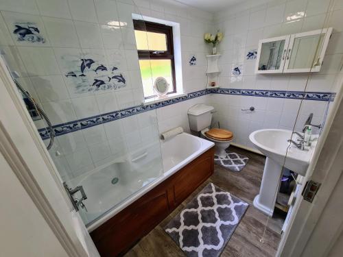 a bathroom with a tub and a toilet and a sink at Knobbly Nook, whole property, gardens, parking, wifi, relaxing near Eden Project and coast in Saint Blazey