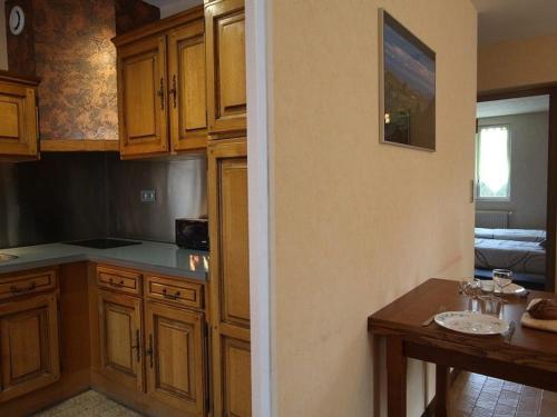 une cuisine avec des armoires en bois et une table à l'intérieur dans l'établissement Charmante Maison Traditionnelle avec Jeux, Terrasse et Parking à Lantriac - FR-1-582-78, à Lantriac