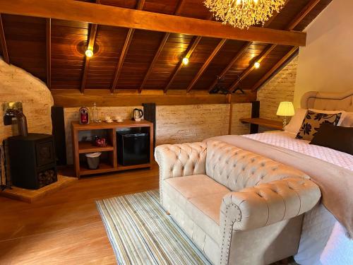 a bedroom with a bed and a couch and a tv at Pousada Dona Bendita in Monte Verde