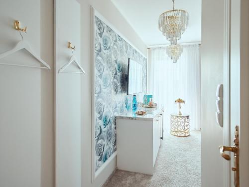 a white hallway with a chandelier and a room at La Rose Residence in Mikołajki