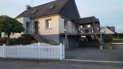 a house with a white fence in front of it at Chambres au Village in Saint-Mʼhervé