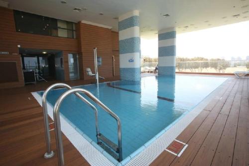 West All Suites Hotel Ashdod في أشدود: مسبح كبير في عمارة ذات أرضية خشبية