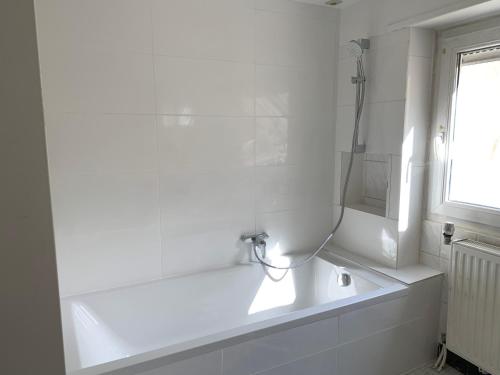 a white bathroom with a bath tub and a window at Nice rooms in Beggen house - In Luxembourg city in Luxembourg