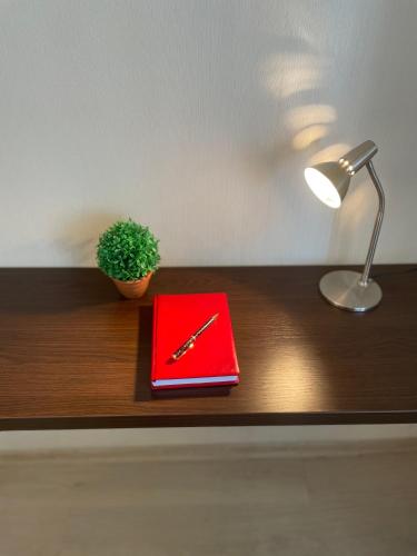 a red book on a table with a lamp and a pen at Однокімнатні апартаменти на Майдані, дистанційне заселення 24х7 in Kyiv