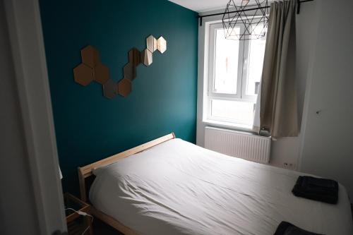 - une chambre avec un lit blanc et un mur bleu dans l'établissement La petite Citadelle - l'appartement, à Namur