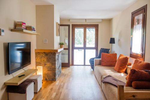 een woonkamer met een bank en een tv bij El Descanso del Sol - Apartamento en Pirineos in Plan