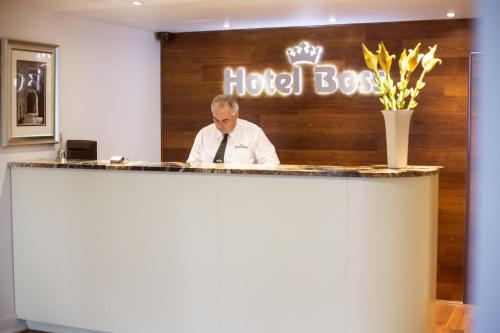 a man standing in front of a counter with a sign on it at Hotel Boss in Łódź