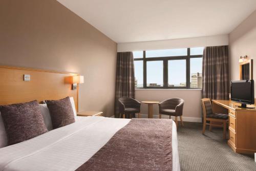 ノッティンガムにあるラマダ ノッティンガム シティ センターのベッドとテレビが備わるホテルルームです。