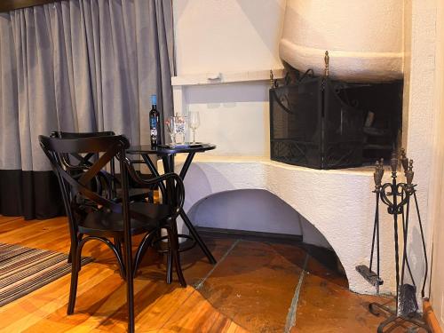 a table and chair in a room with a fireplace at Pousada Dona Bendita in Monte Verde
