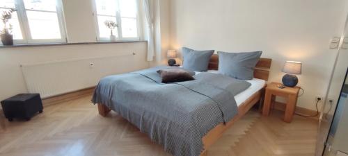 a bedroom with a bed with blue sheets and two windows at Apartment Madrid in Mühlhausen
