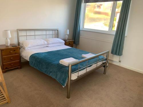 a bedroom with a bed with a blue blanket and a window at Modern & Light with Sea Views & Parking, Swansea in Dunvant