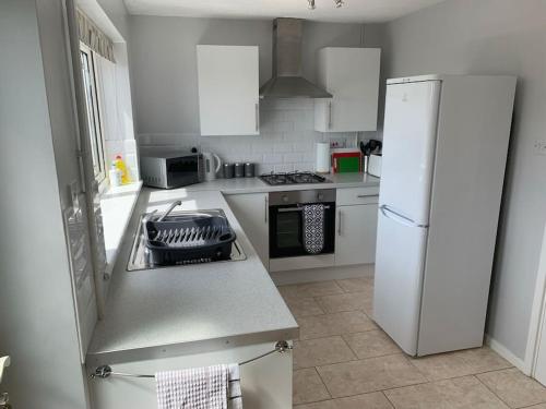 a kitchen with white appliances and a white refrigerator at Modern & Light with Sea Views & Parking, Swansea in Dunvant