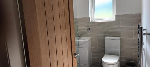 baño con aseo y lavabo y ventana en Modern two bedroom house near beach/ Durham City en Hawthorn