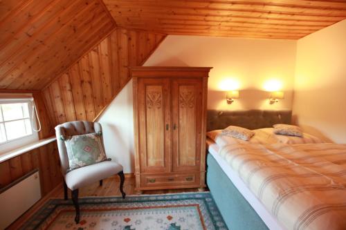 ein Schlafzimmer mit einem Bett und einem Stuhl in einem Zimmer in der Unterkunft Alte Scheune in Ahrenshoop