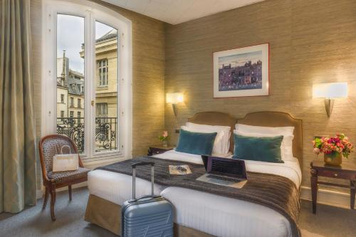 a hotel room with a bed with a laptop on it at Hôtel Delavigne in Paris