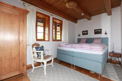 sypialnia z niebieskim łóżkiem i krzesłem w obiekcie Fachwerkhaus w mieście Ahrenshoop