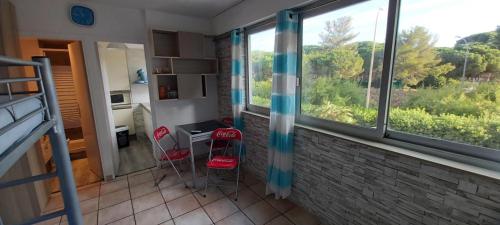 Cette chambre dispose de deux chaises, d'un bureau et d'une fenêtre. dans l'établissement Le Zodiaque 20m2 piscine, à Hyères