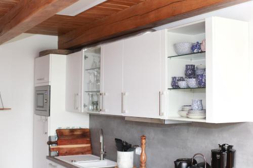 a kitchen with white cabinets and a sink at Fachwerkhaus in Ahrenshoop