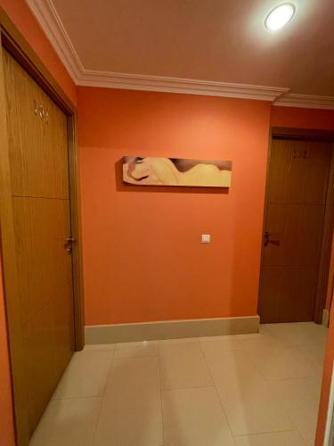 a hallway with an orange wall and two doors at Hostal Santiago 2 in Burgos