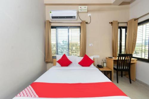 a bedroom with a bed with red pillows and a desk at Grand Inn in Hāora