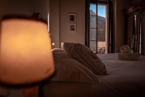 a bedroom with a bed with a lamp and a window at Hotel Mas de Xaxas in Camprodon